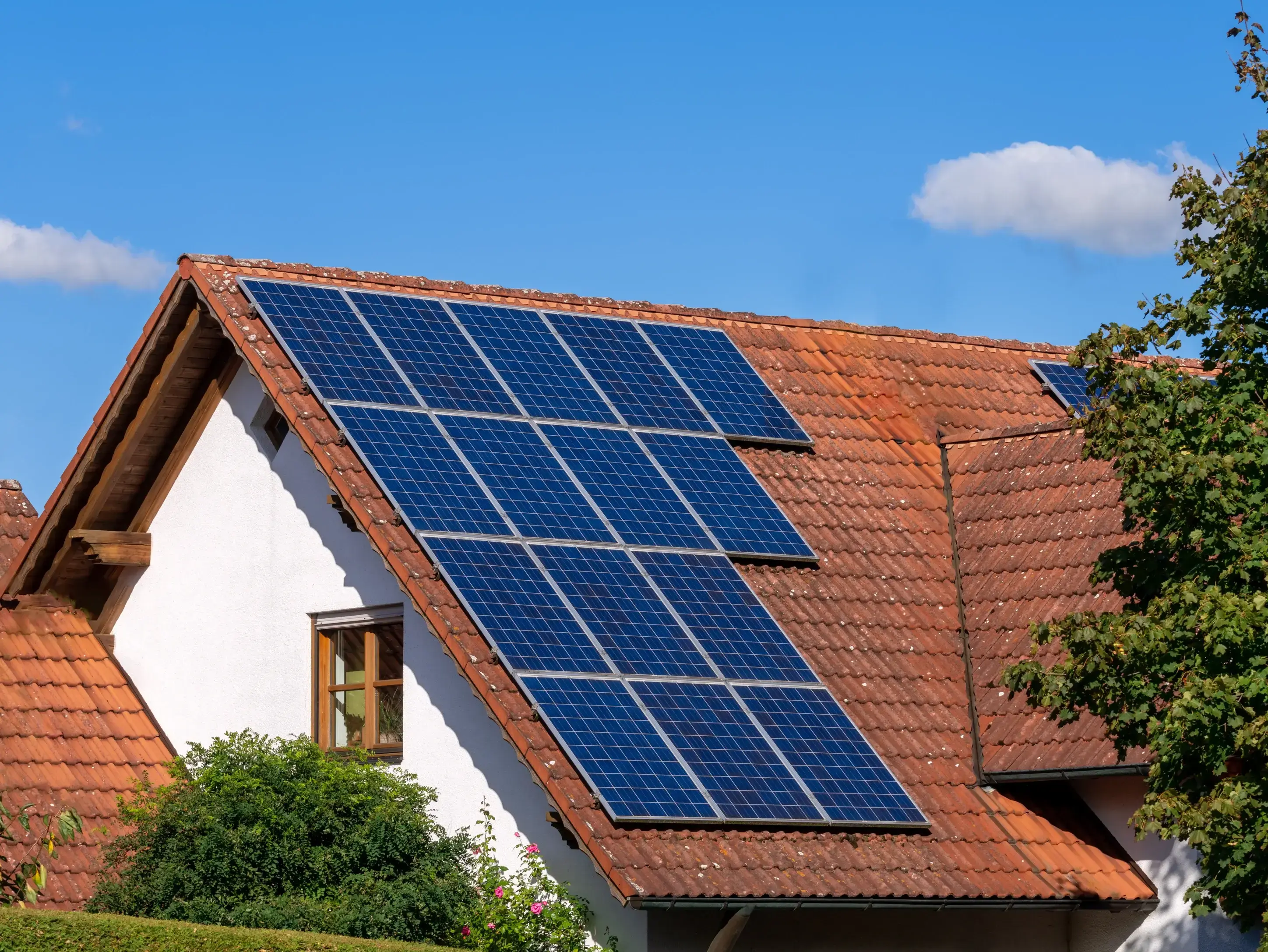 Solar panels installed on a red tile roof of a residential home under clear blue sky